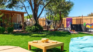 A backyard with a wooden table, a hammock, and a play area with a colorful mural.