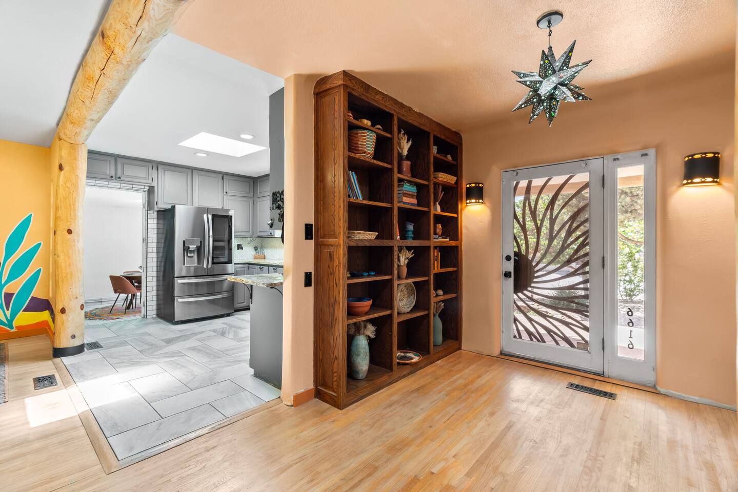 A modern kitchen with a built-in refrigerator, wooden shelving, and a decorative ceiling light.