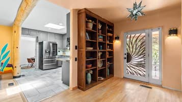 A modern kitchen with a built-in refrigerator, wooden shelving, and a decorative ceiling light.