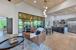 A modern interior with a leather sofa, dining area, kitchen, and large windows. - The W Retreat • Sauna • Hot Tub • 2 King Suites (Sevierville)