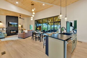 A modern kitchen with a large island, a dining area, and a living space with a fireplace. - The W Retreat • Sauna • Hot Tub • 2 King Suites (Sevierville)