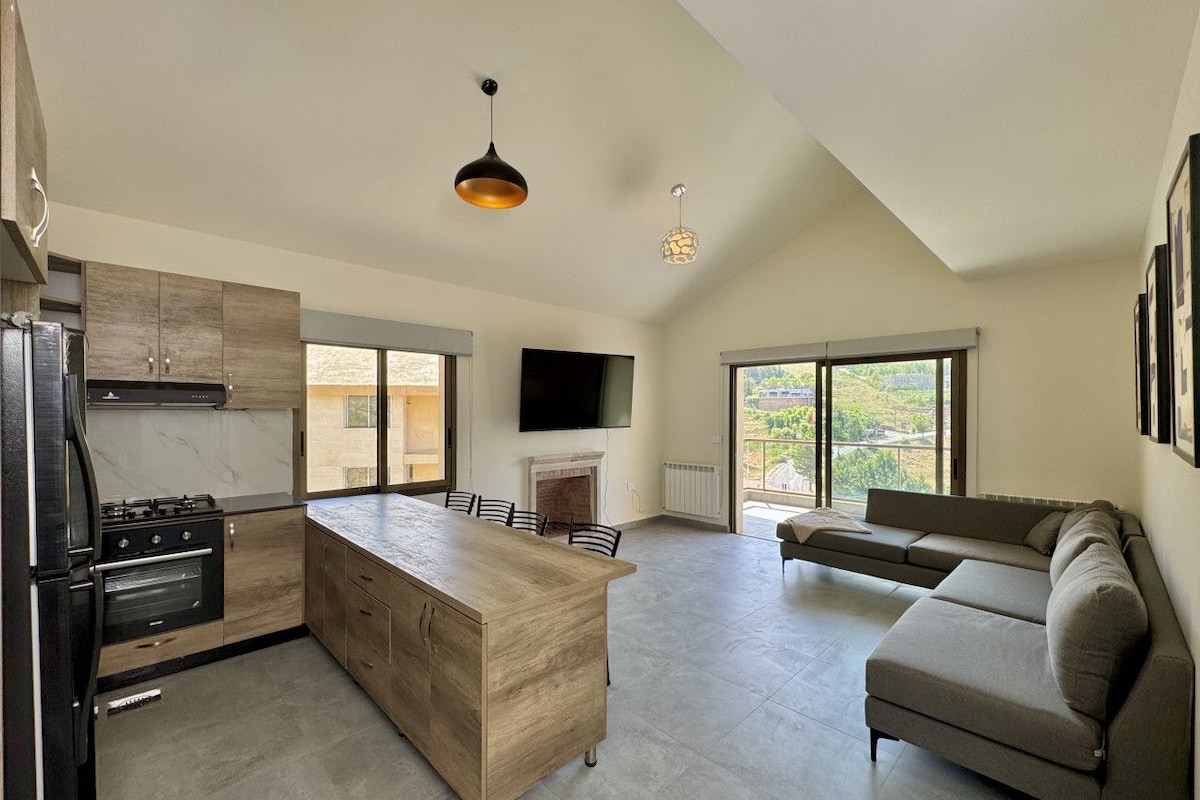 A modern kitchen with a central island, a dining area, and a living space with a sofa.