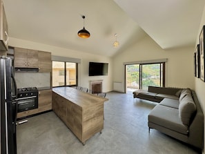 A modern kitchen with a central island, a dining area, and a living space with a sofa. - Faqra Chalets by Stayinn (Faqra)
