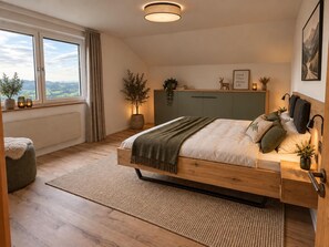 A bedroom with a bed, bedside table, lamp, window, and view. - Freiraum Vacation Rental (Riefensberg)