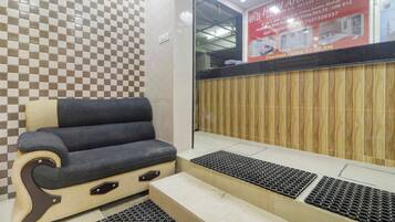 Zona de recepción de un hotel con un estampado de cuadros en la pared, un mostrador de recepción, un área de estar con una silla acolchada y un panel de pared de madera.