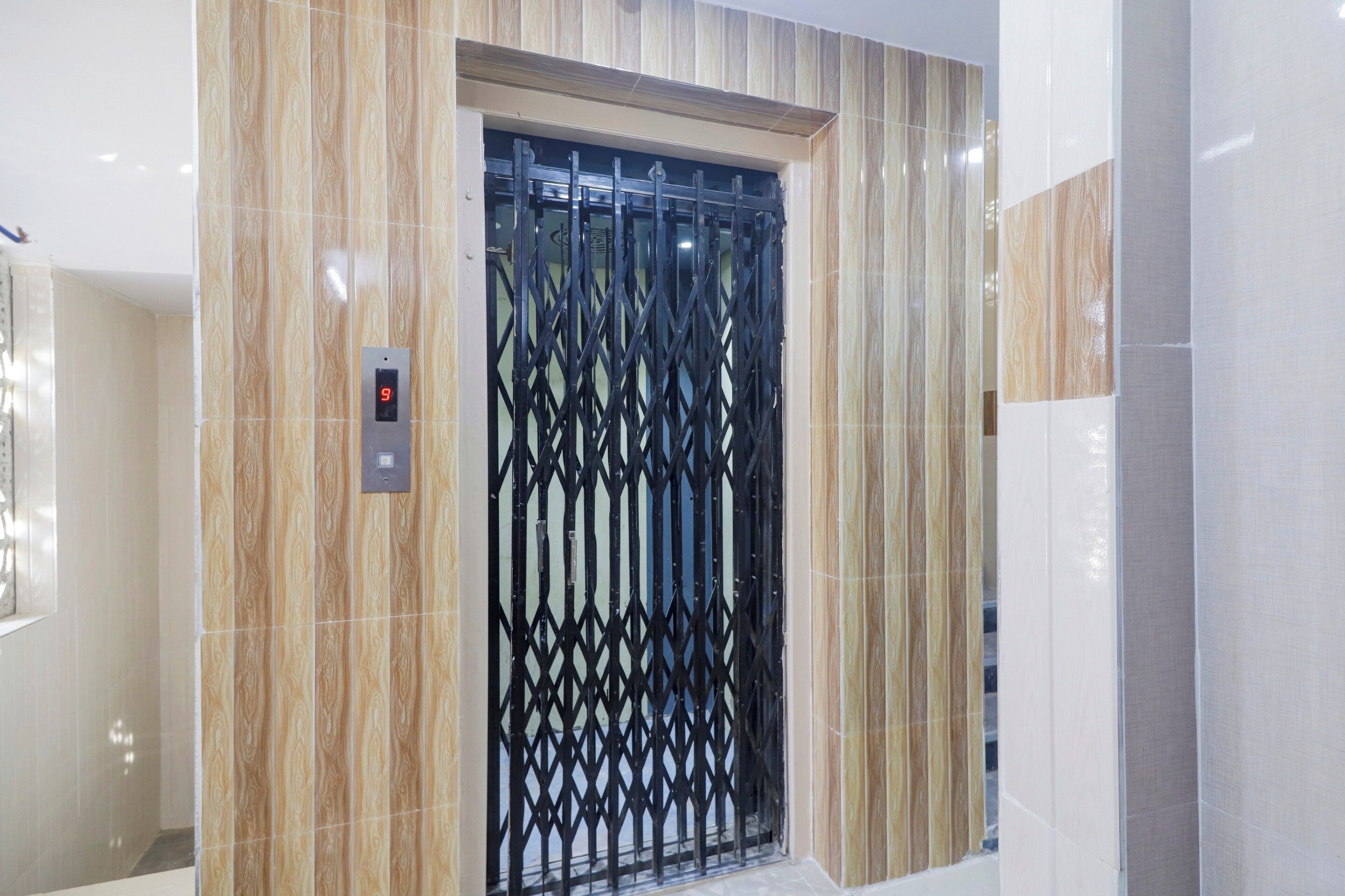 Un ascensor con pantalla digital y una puerta de seguridad metálica.