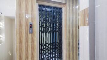 Un ascensor con pantalla digital y una puerta de seguridad metálica.