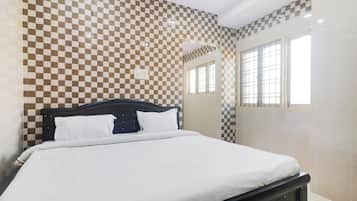 Un dormitorio con un estampado de cuadros en la pared, una cama con ropa blanca y un ventanal con vistas.