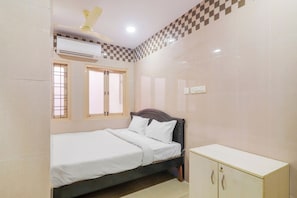 A bedroom with a bed, a wardrobe, an air conditioning unit, and a ceiling fan.
