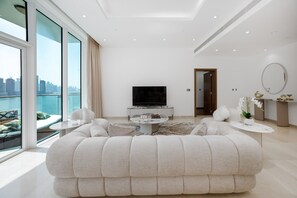 Een moderne woonkamer met een grote bank, een televisie en uitzicht op de stad.