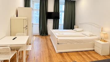 A hotel room with a bed, a desk, chairs, a television, and a wardrobe.