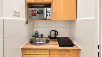 A compact kitchen with a built-in microwave, a kettle, and a sink.