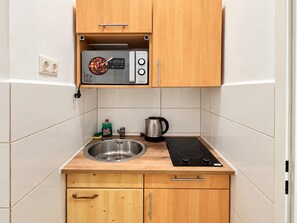 A compact kitchen with a built-in microwave, a kettle, and a sink. - Vienna Hideaway 1BR near Westbahnhof (Wien)