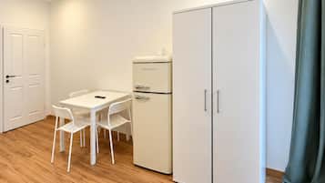 A room with a white table and chairs, a white refrigerator, and a wardrobe.