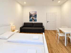 A bedroom with a bed, a sofa, a desk, and a chair. - Vienna Hideaway 1BR near Westbahnhof (Wien)