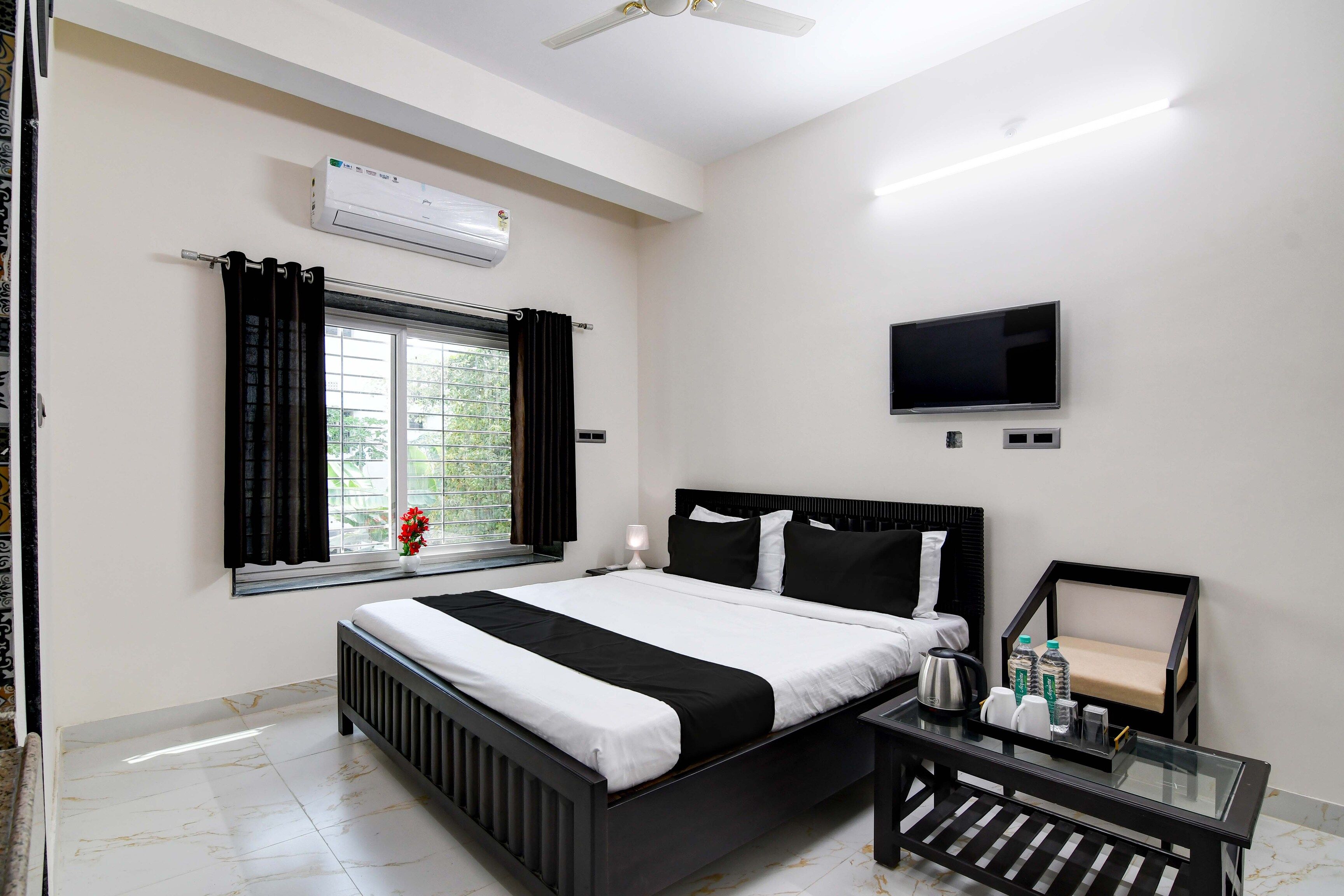 Habitación de hotel con cama, televisor, ventana con cortinas y radiador.