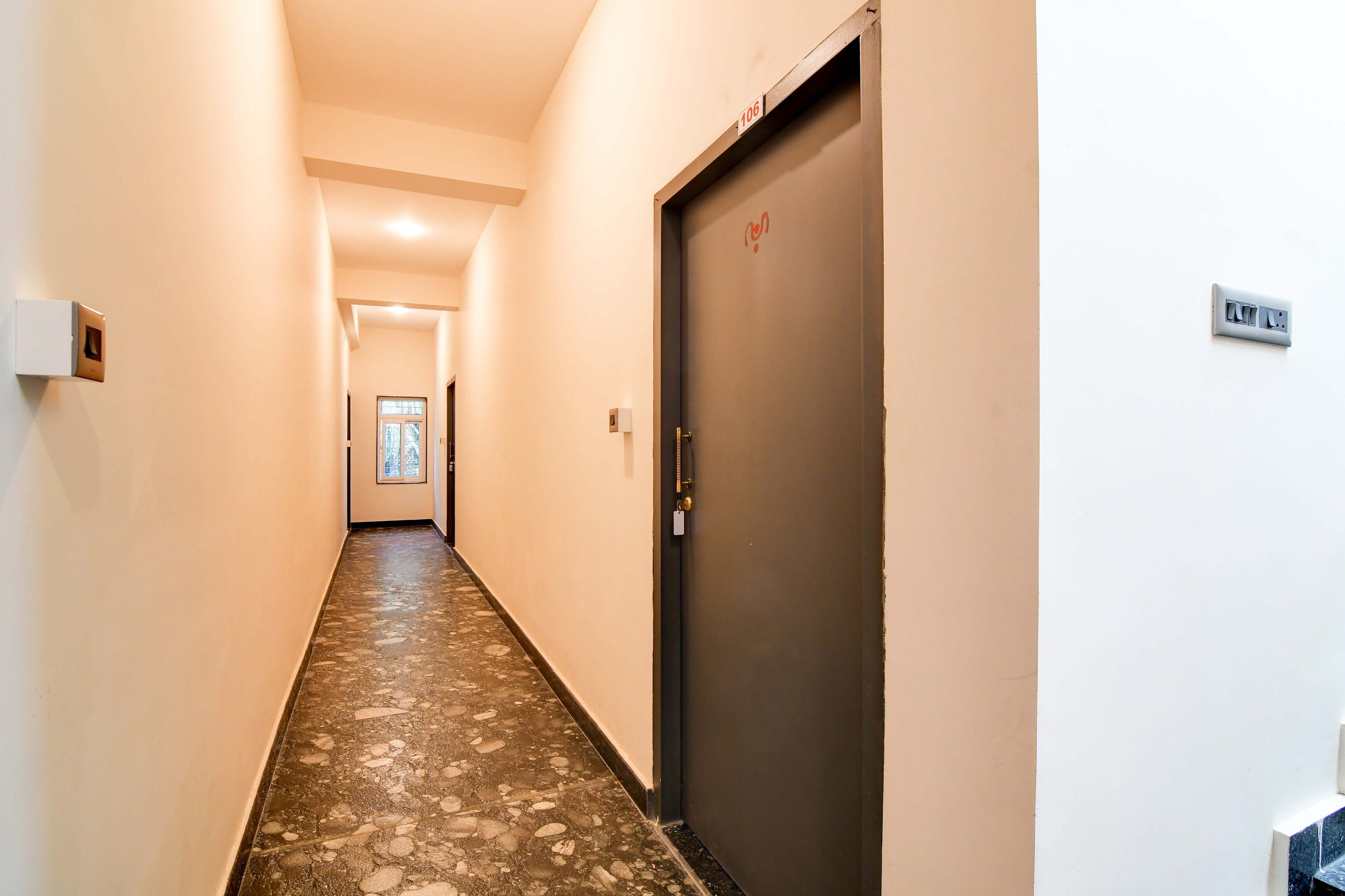 A hallway with a door marked '106', a light switch, and a wall-mounted electrical outlet.