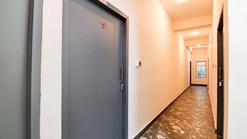 Un pasillo con una puerta cerrada marcada con el número 103, un interruptor de luz y un timbre.