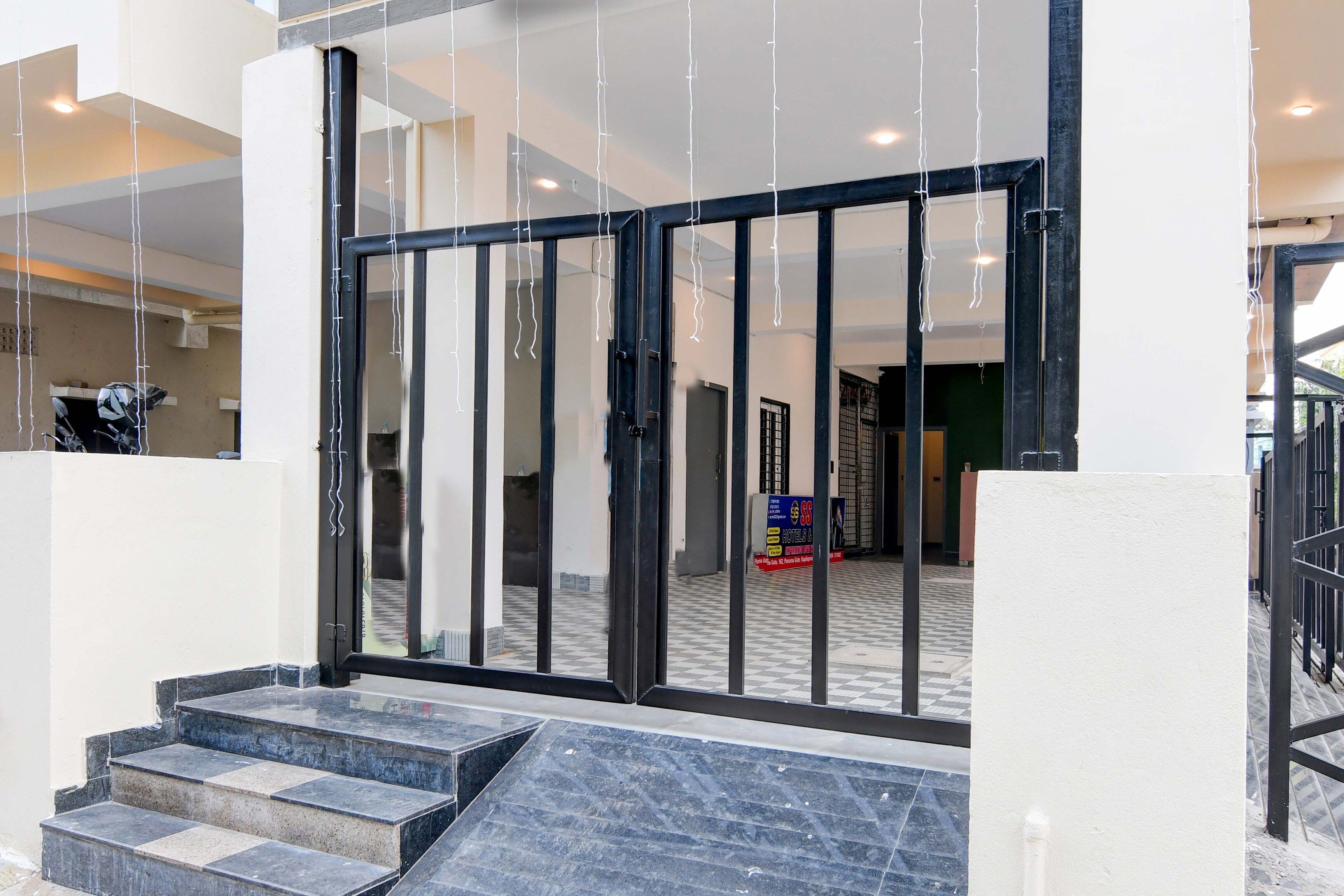 A hotel entrance with a glass door, a staircase leading up, and a tiled floor.