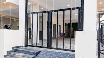 A hotel entrance with a glass door, a staircase leading up, and a tiled floor.