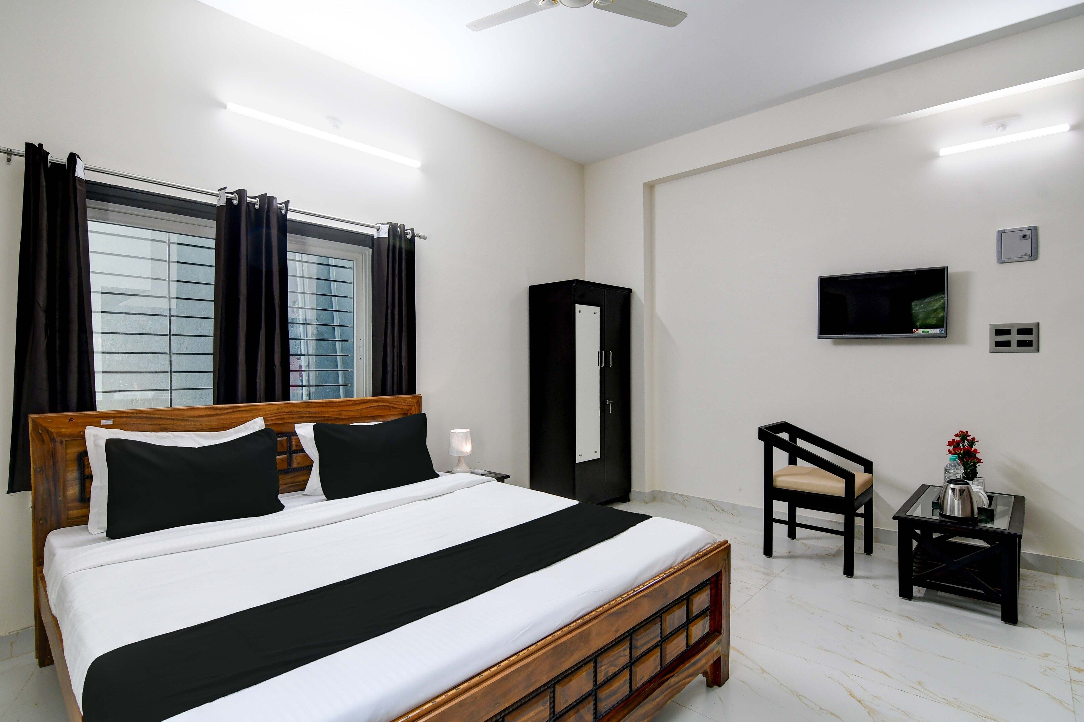 A hotel room with a bed, a TV, a desk, and a chair.
