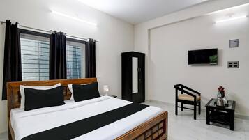 A hotel room with a bed, a TV, a desk, and a chair.