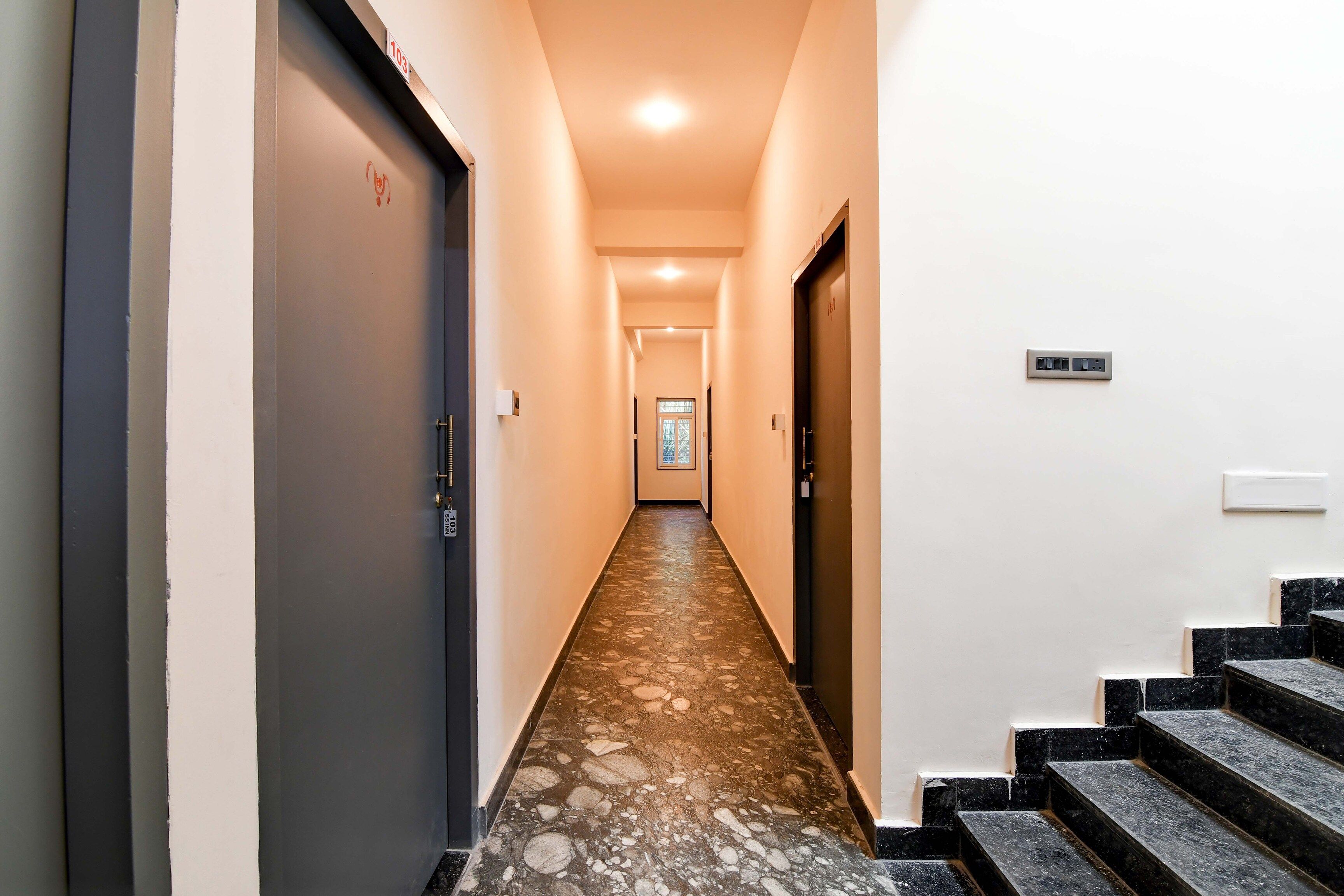 A hallway with a marble floor leading to a staircase.