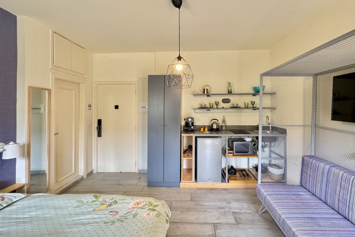 Quarto compacto com cama, sofá, cozinha compacta e área de jantar.