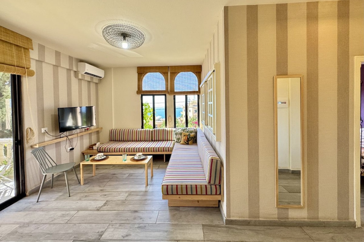 Uma sala de estar com sofá, televisão e janela com vista.