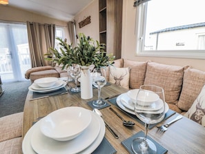 A dining area with a wooden table set for four, including plates, glasses, and cutlery. - Gosling 14 (Scarborough)