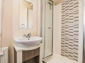 A bathroom with a white sink, a glass shower enclosure, and a tiled shower wall. - Gosling 14 (Scarborough)