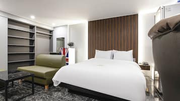 A hotel room with a bed, a seating area, a wardrobe, and a mirror.