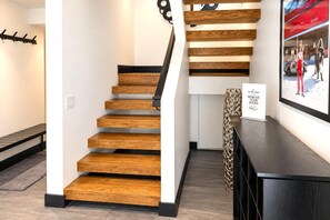 Eine moderne Treppe mit Holzdielen und schwarzen Geländern, die zu einem Podest mit einem Willkommensschild führt.