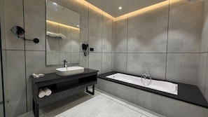 Ein modernes Badezimmer mit einem großen Spiegel, einem Waschbecken und einer Badewanne.