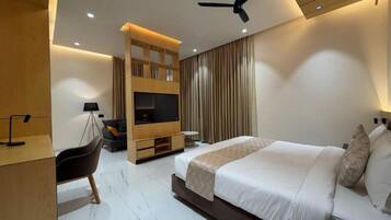 Una habitación de hotel moderna con cama, escritorio, silla, televisor y ventilador de techo.