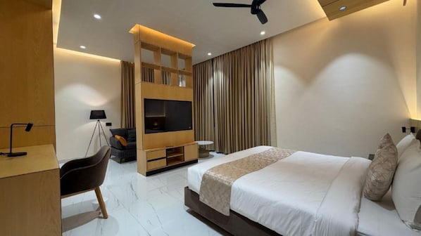 Ein modernes Hotelzimmer mit Bett, Schreibtisch, Stuhl, Fernseher und Deckenventilator.