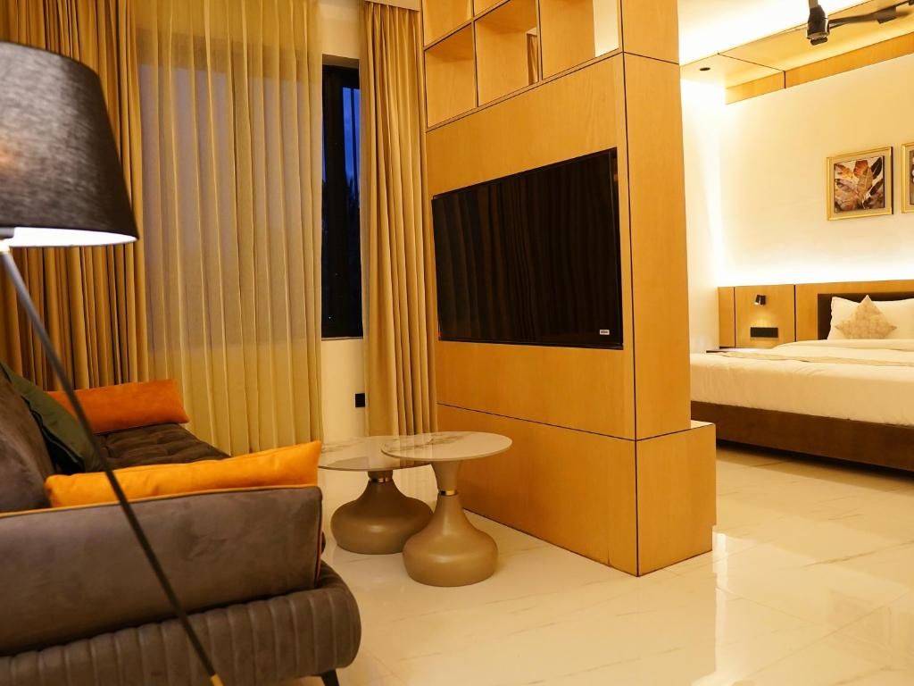 Una habitación de hotel moderna con sofá, una mesita redonda, televisión y cama.