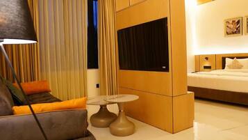 Una habitación de hotel moderna con sofá, una mesita redonda, televisión y cama.