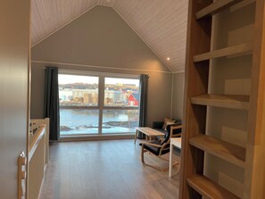 A room with a large window, a wooden floor, a table, and a chair.