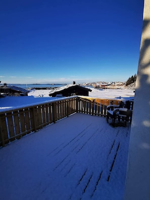 Um deck coberto de neve com vista para a costa e edifícios ao longe.