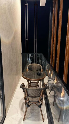 Ein modernes Interieur mit einer Glaskabine, einem runden Tisch, zwei Korbstühlen und dunklem Hintergrund.