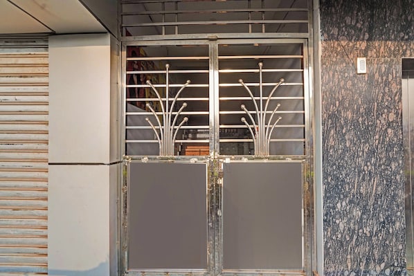 Um portão de metal com design decorativo em barras, uma porta cinza e uma parede texturizada.