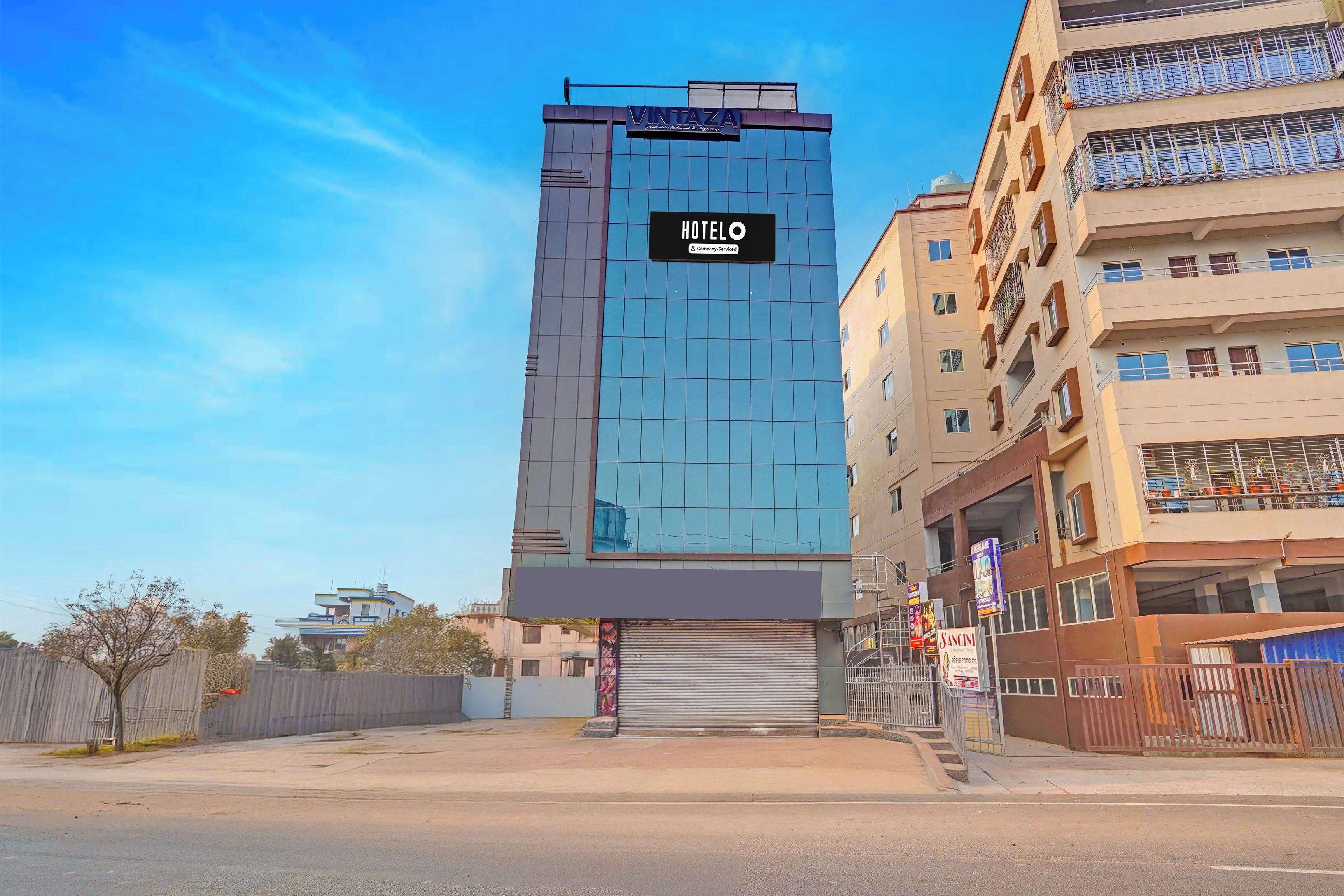 A modern hotel building with a prominent sign indicating it is a company-serviced hotel.