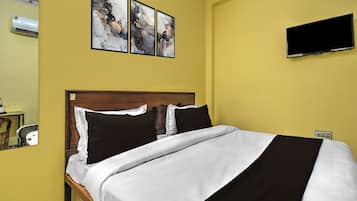 A hotel room with a bed, a flat-screen TV, and three abstract paintings on the wall.