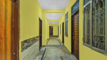 A hallway with yellow walls, wooden doors, and patterned windows.