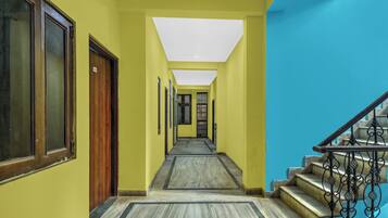 A hallway with a wooden door, a staircase with metal railings, and a tiled floor.