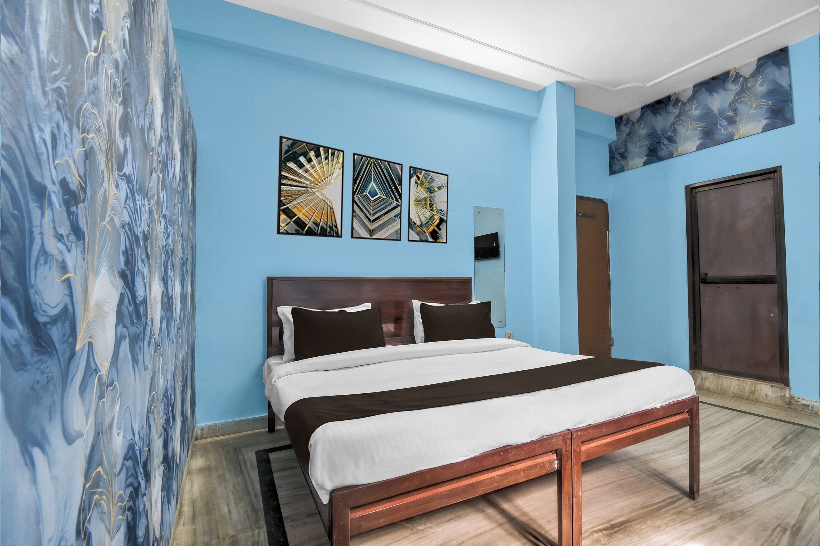 A hotel room with a bed, artwork on the wall, a door, and a window.