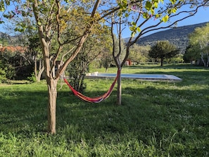 A hammock tied between two trees in a grassy area with a pool in the background. - Holiday Home 'La Valkyrie' with Mountain View, Wi-Fi and Air Conditioning (Caudiès-de-Fenouillèdes)