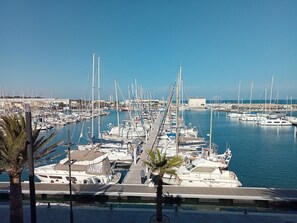 En havn med mange både i havnen, en klar himmel og et roligt hav.
