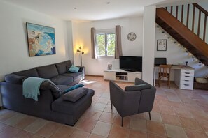 A living room with a sofa, a chair, a TV, and a staircase. - Holiday Home 'La Valkyrie' with Mountain View, Wi-Fi and Air Conditioning (Caudiès-de-Fenouillèdes)